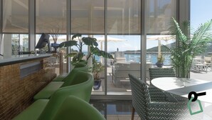 Un moderno vestíbulo de hotel con un mostrador de recepción, asientos verdes y vistas al mar a través de amplias ventanas.