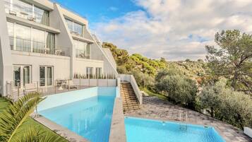 Un moderno edificio de dos pisos con una piscina y una escalera que lleva a un balcón.