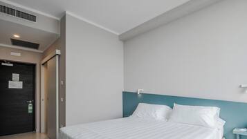 A modern hotel room with a large bed, a nightstand, and a door with a sign.