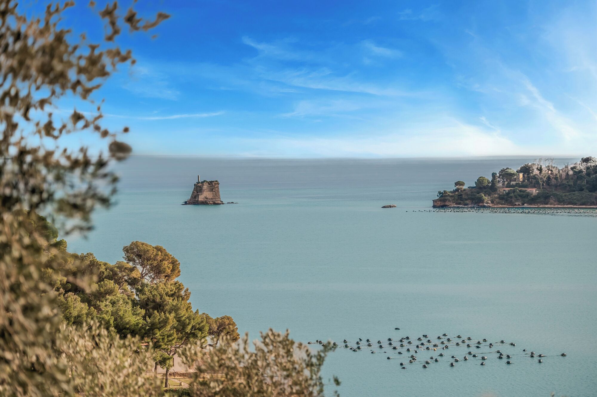 Un paisaje costero con un afloramiento rocoso destacado y una isla distante con vegetación.