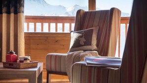 A cozy room with a wooden deck, a striped armchair, a cushion with a deer design, and a tray with jars and a red container. - lesetoilesdelaplagne.com les montagnettes foot slopes (La Plagne-Tarentaise)