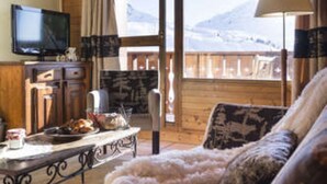 A cozy living room with a sofa, a coffee table, and a television. There is a view of mountains through a large window. - lesetoilesdelaplagne.com les montagnettes foot slopes (La Plagne-Tarentaise)