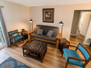 Uma sala de estar com sofá, duas poltronas, mesa de centro e mesa de pebolim.