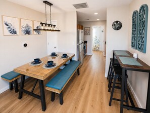 Uma sala de jantar com uma mesa de madeira, bancos acolchoados azuis e um lustre.