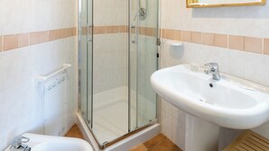 A bathroom with a glass shower enclosure, a pedestal sink, and a vanity with a mirror. - Apartments i Mirti Bianchi (Santa Teresa di Gallura)