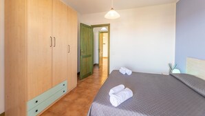 A bedroom with a large wardrobe, a bed with rolled towels, and a hallway leading to another room. - Apartments i Mirti Bianchi (Santa Teresa di Gallura)