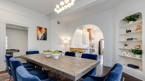 A dining area with a wooden table, blue upholstered chairs, and a chandelier. - Luxury Retreat Near San Antonio Icons (San Antonio)