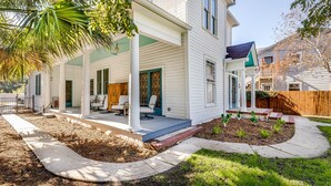 A two-story house with a covered porch, a front yard with a small garden, and a wooden fence. - Luxury Retreat Near San Antonio Icons (San Antonio)