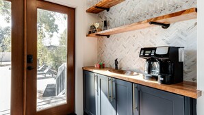 A kitchen with a coffee maker, wooden shelves, and a herringbone-patterned backsplash. - Luxury Retreat Near San Antonio Icons (San Antonio)