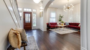 A spacious living room with a red sofa, a wooden bench, and a chandelier. - Luxury Retreat Near San Antonio Icons (San Antonio)