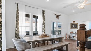 Un comedor con mesa de madera, sillas de mimbre, un banco y un ventilador de techo.