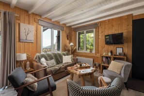 Un salon chaleureux avec un décor intérieur en bois, un canapé, une table basse et un téléviseur.