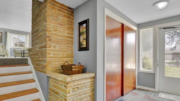 A staircase with a stone wall, a wooden bench, and a door with a metal gate. - Comfort and Space near MSU (Lansing)
