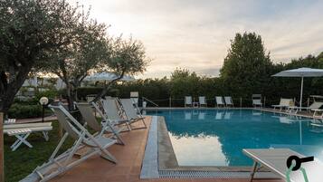 En sÀsongsöppen utomhuspool, parasoller och solstolar