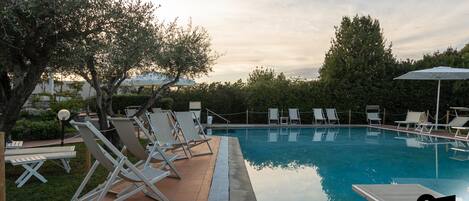 Una piscina al aire libre de temporada, sombrillas