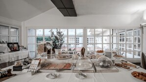 Montaje de bufé de desayuno con diversas opciones de comida y un ventanal que proporciona luz natural.