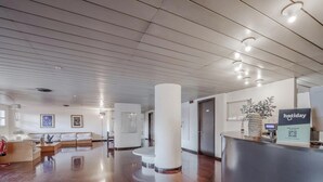 Un vestíbulo de hotel con mostrador de recepción, zona de estar y un pilar grande.