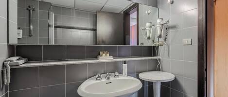 Un baño moderno con un espejo grande, un lavabo y un secador de pelo montado en la pared.