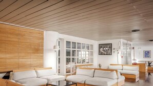 Una sala de estar moderna con suelo de madera, un ventanal grande y un juego de sofá.