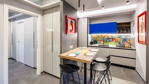 Une cuisine moderne avec une table en bois, deux tabourets de bar et un mur de crédence aux couleurs vives.