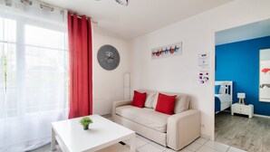 A modern living room with a white sofa, red cushions, a white coffee table with a plant, a large wall clock, and a blue accent wall.