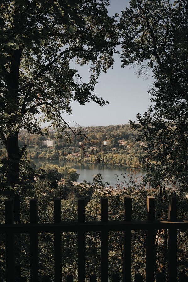 A view of a lake surrounded by trees and buildings, with a wooden fence in the foreground. - Cabane de la Saône by Lyon Country House (Caluire-et-Cuire)