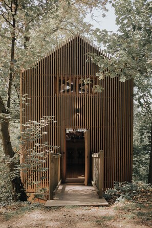 A wooden structure with vertical slats, a central door, and a wooden pathway leading to it. - Cabane de la Saône by Lyon Country House (Caluire-et-Cuire)