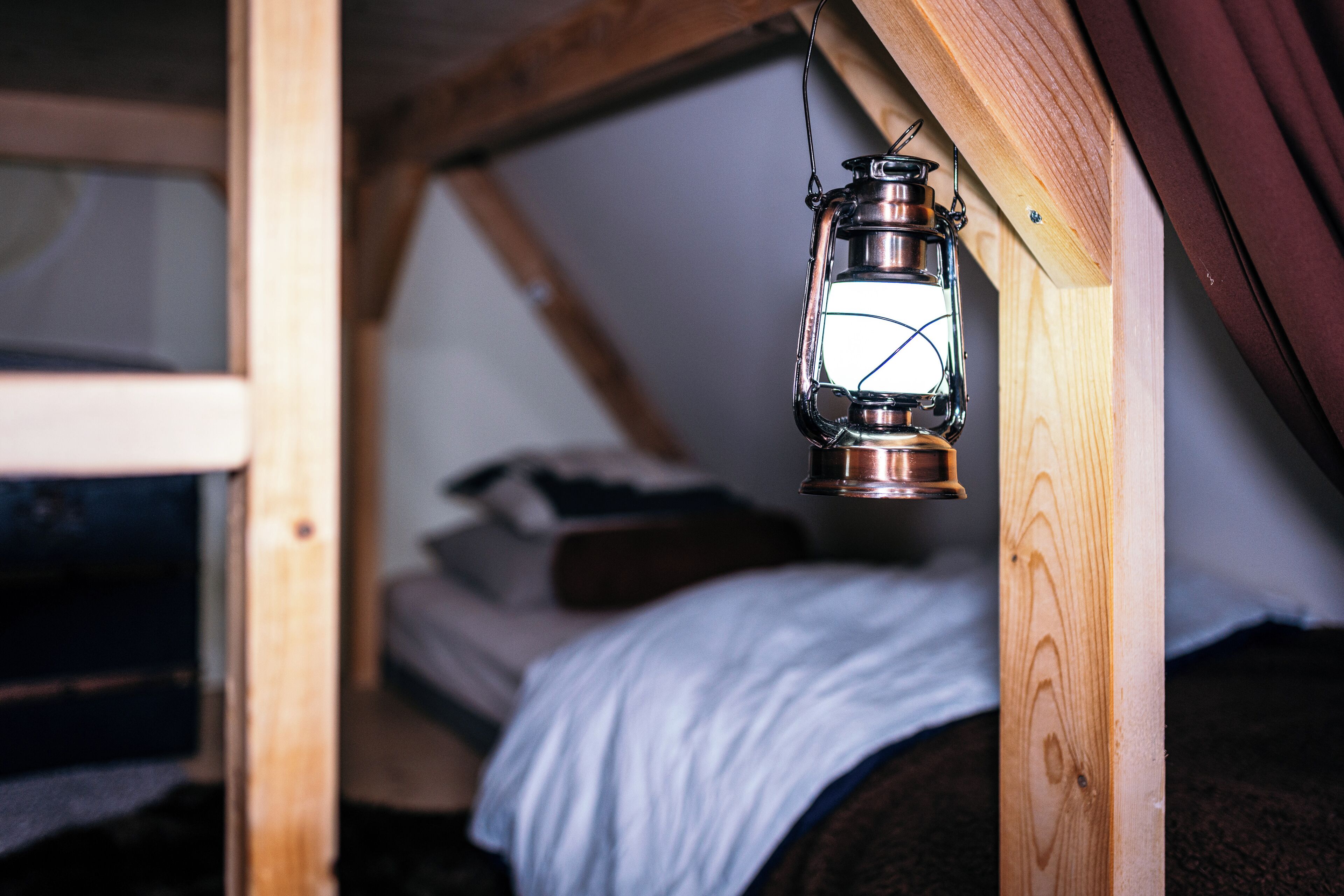 Een slaapkamer met een vide, gemaakt van hout, met een metalen lantaarn boven het bed.