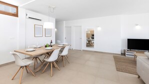 Un salon moderne avec un grand téléviseur à écran plat, une table basse en bois et un canapé beige.