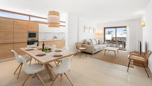 A modern apartment with a dining area, kitchen, living room, and balcony.