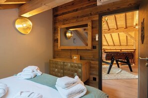 A hotel room with a bed, a wooden headboard, a mirror, and a view of the outdoor area.