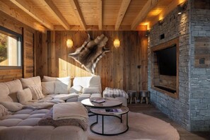 A cozy living room with a stone fireplace, wooden walls, and a leather hide mounted on the wall.