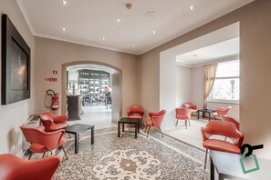 A hotel lobby with a bar area, red chairs, a patterned rug, and a fire extinguisher. - Hotiday Room Collection - Stresa (Stresa)
