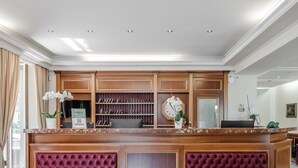 Un comptoir d’accueil d’hôtel avec un revêtement en bois, une horloge et une plante.