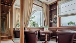 Une chambre d’hôtel dotée d’un coin salon, d’une bibliothèque et offrant une vue sur l’extérieur.