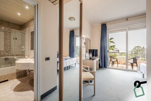 A hotel room with a bathroom, a desk, a chair, and a balcony with a view. - Hotiday Room Collection - Stresa (Stresa)