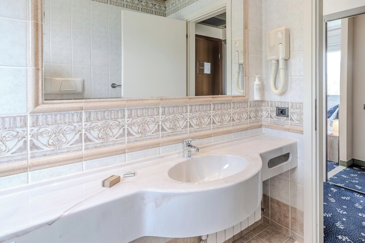 A bathroom with a large mirror, a sink, and a toilet.
