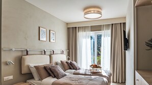Een moderne hotelkamer met twee bedden, een flatscreen-tv, een klein tafeltje met fruit en uitzicht op een balkon.