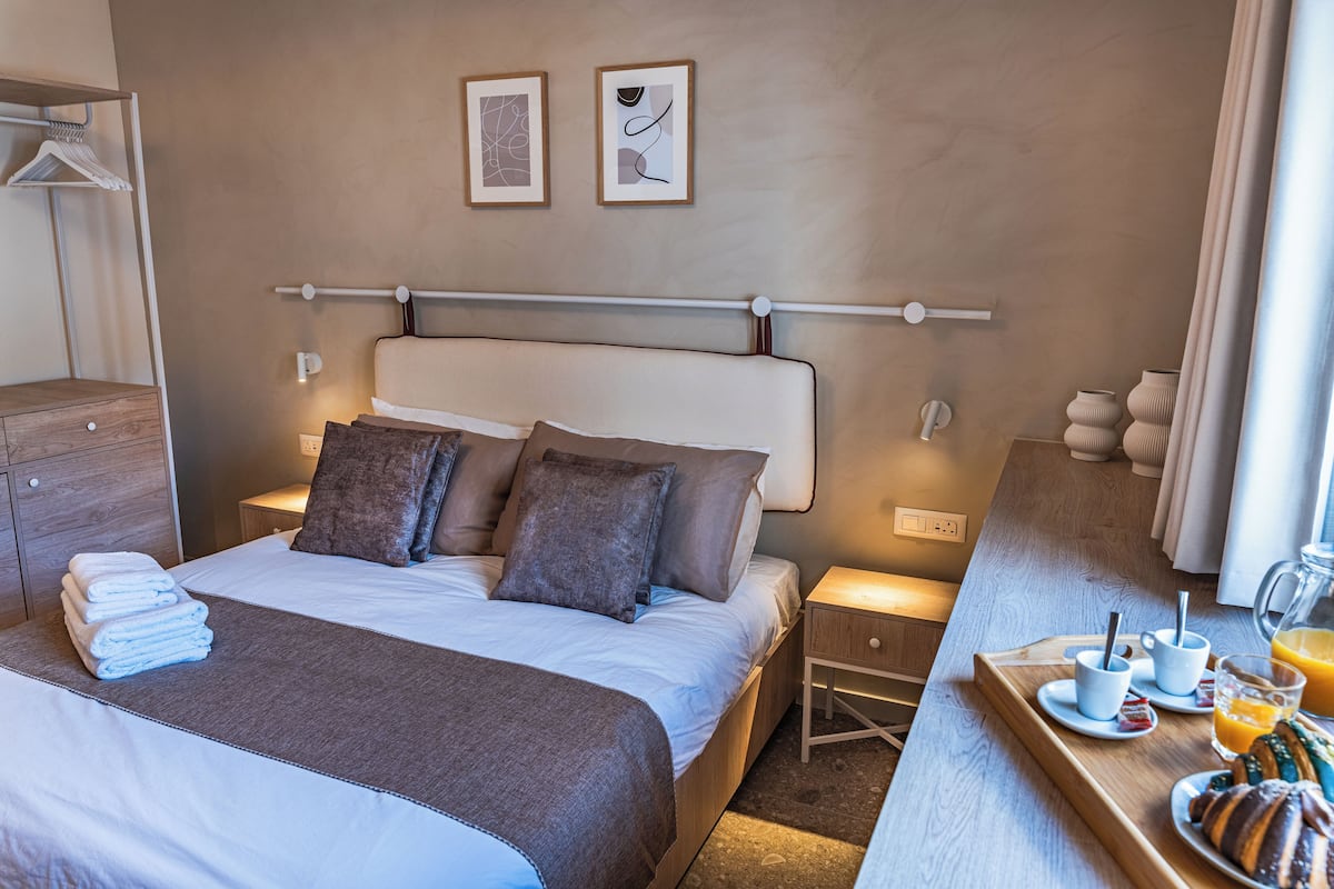 Habitación de hotel con cama, mesitas de noche, una bandeja de desayuno y una obra de arte en la pared.