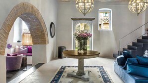 A spacious lobby with a brick archway, a round table with a vase of flowers, a staircase, and a blue sofa. - AMORE RENTALS - Villa Viola with Pool, Garden, Ideal for Weddings (Sarteano)