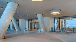 Un hall d’entrée spacieux, doté de grandes colonnes, d’un éclairage moderne et offrant une vue sur l’extérieur.