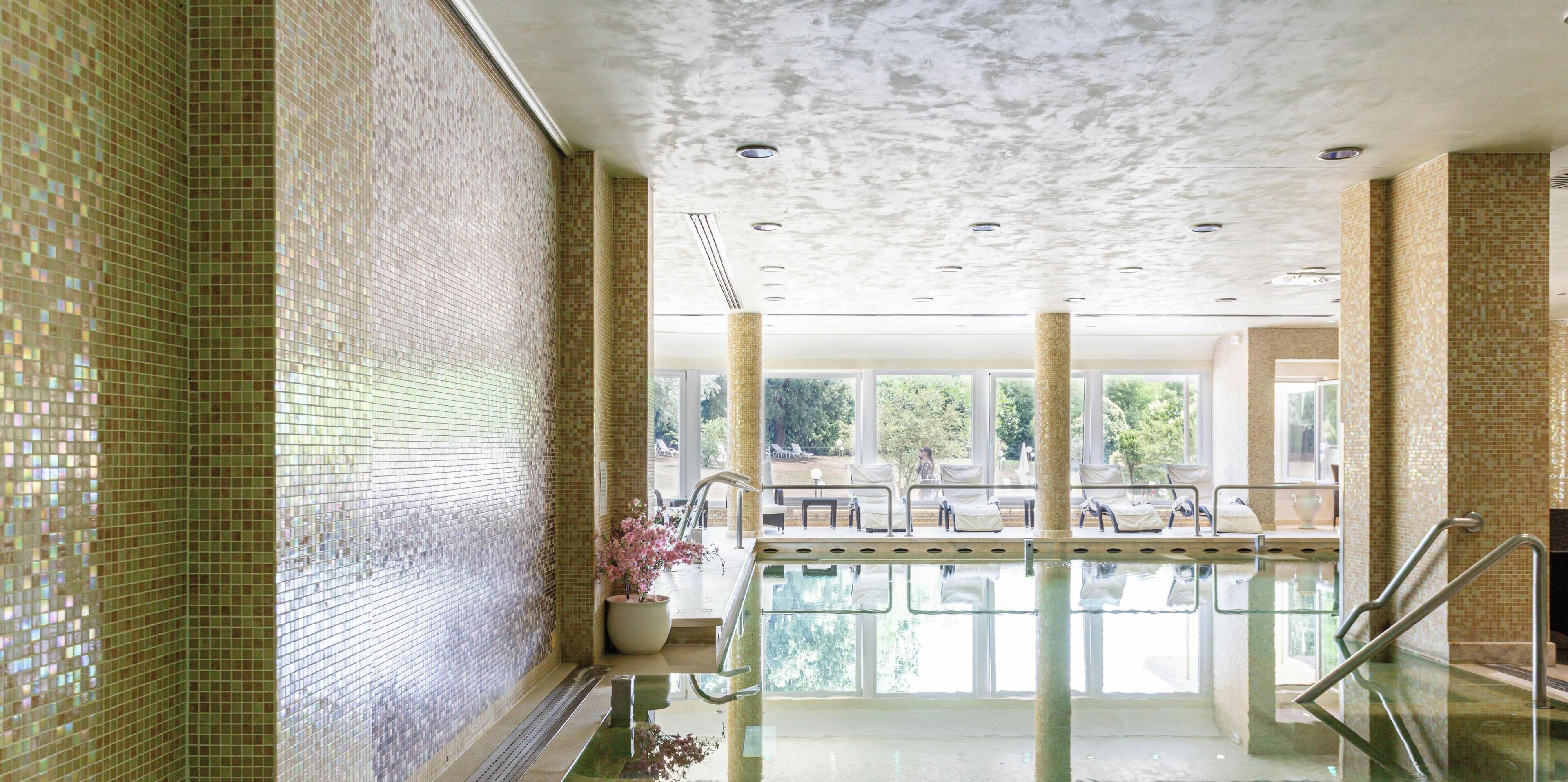 Ein Poolbereich mit gefliesten Wänden, einer Glasbarriere und Blick ins Freie.