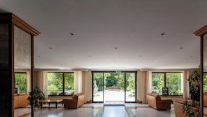 A spacious lobby with a high ceiling, large windows, and a view of the outdoor area. - Hotiday Room Collection - Fiuggi (Fiuggi)