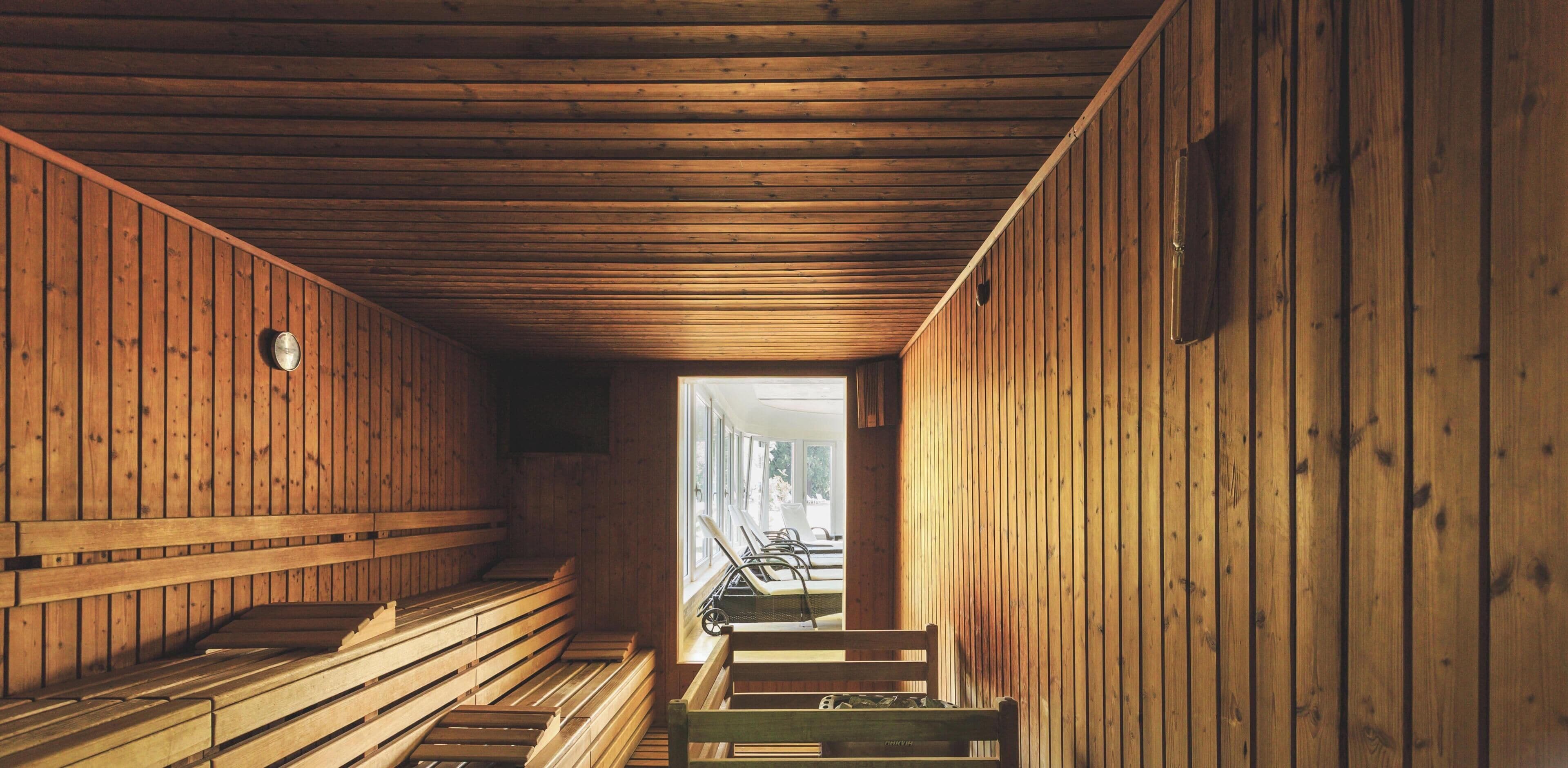 A sauna room with wooden benches and a bench in the foreground.