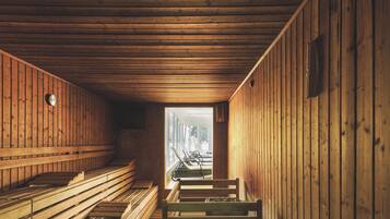 A sauna room with wooden benches and a bench in the foreground.