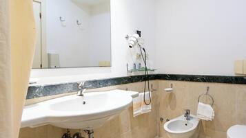 A bathroom with a sink, bidet, and mirror.