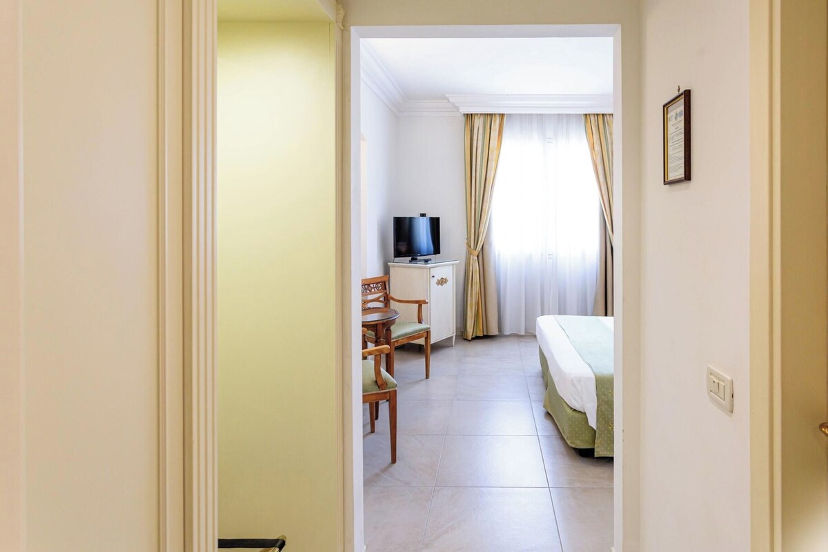 Ett hotellrum med en säng, ett skrivbord med en tv och en stol.