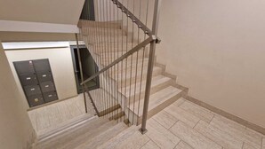 A staircase with metal railings and a tiled floor. - 1-bedroom in city center | balcony | close to the Main Square and Jewish Quarter (Kraków)