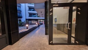 A modern hotel entrance with a glass door and a pathway leading to a building with multiple floors and balconies. - 1-bedroom in city center | balcony | close to the Main Square and Jewish Quarter (Kraków)