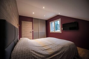 A bedroom with a bed, a wardrobe, a television, and a window. - Chalet Horizon, 11-guest chalet in Gérardmer – Sauna, Jacuzzi (Gérardmer)